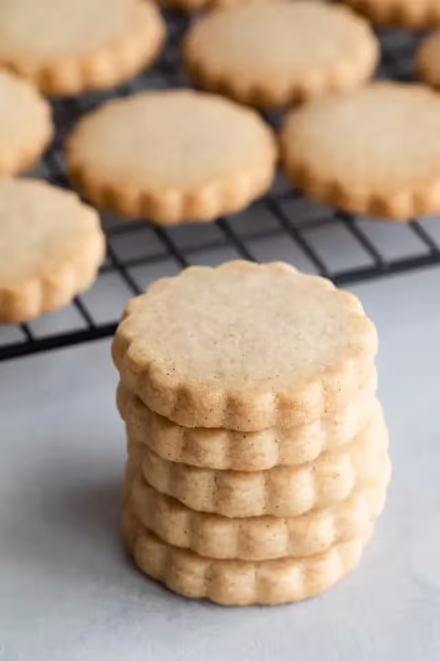 Flower shaped cardamom cookies stacked over each other on a table
