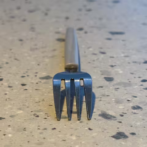 A metal fork placed upside down on a table with its teeth facing front